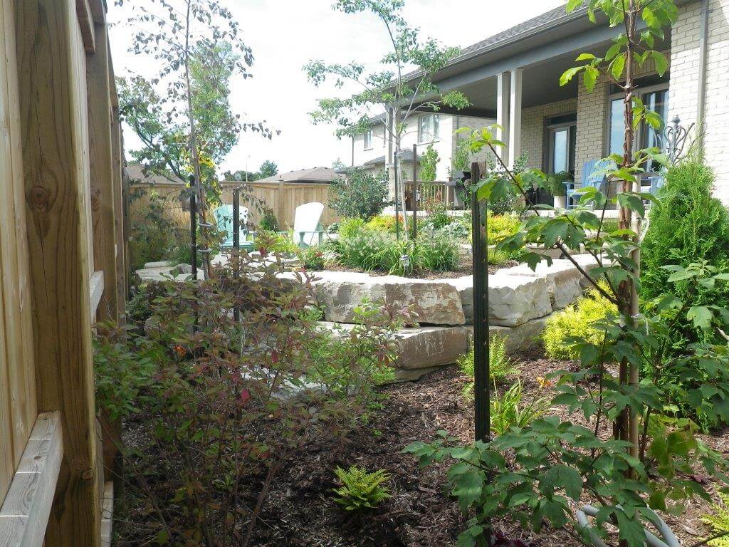 Low-maintenance garden and armour stone retaining wall and patio