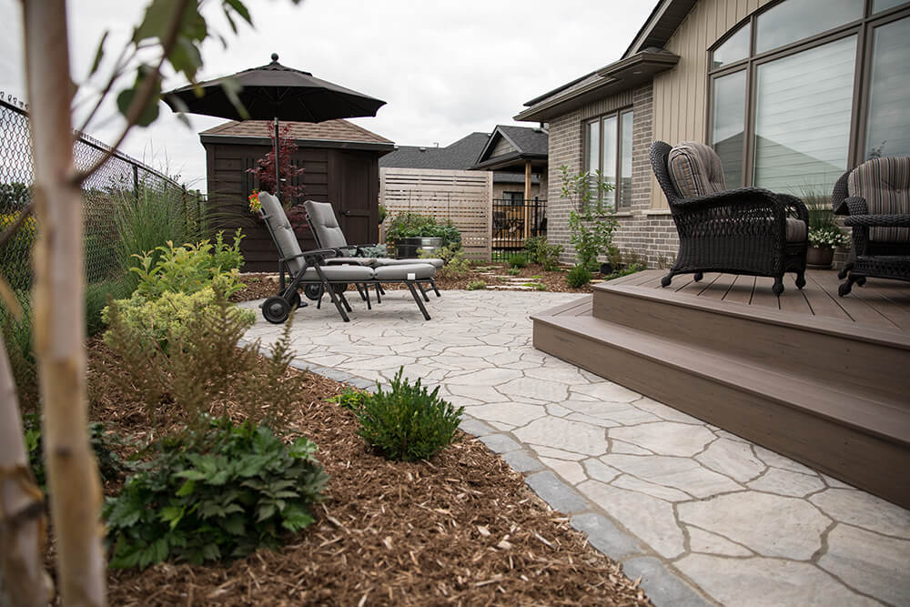 Hardscaping stone patio and surrounding flowerbeds improve outdoor living area and add value